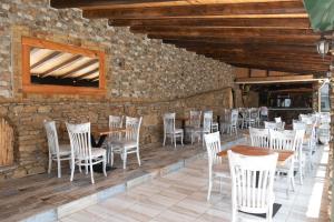 a restaurant with wooden tables and chairs and a stone wall at Mirage Arillas Studio Type B11 in Arillas