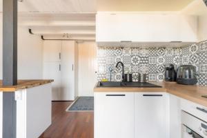 a kitchen with white cabinets and a tile wall at Charmant Studio Mezzanine in Biscarrosse
