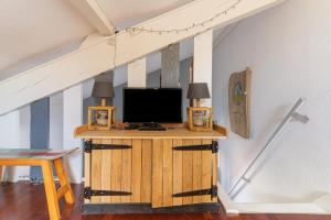 a tv on a wooden stand in a attic at Charmant Studio Mezzanine in Biscarrosse