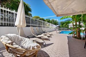 a row of chairs and an umbrella next to a pool at Villa Adele in Gravedona