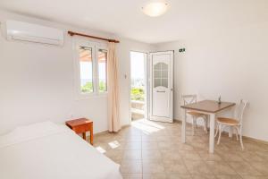 a bedroom with a bed and a desk and a table at Anemologio 203 Tinos in Agios Ioannis