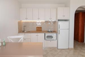 a kitchen with white cabinets and a white refrigerator at Anemologio 203 Tinos in Agios Ioannis