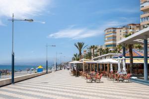 a boardwalk with chairs and umbrellas on a beach at Beachfront Bungalow in Torrox Costa