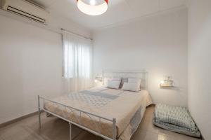 a white bedroom with a bed and a window at Playa Sol Vinaròs in Vinarós
