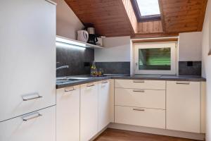 a kitchen with white cabinets and a window at Haus Lohengrin Ferienwohnung 5 in Siusi
