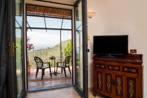 a screened in porch with a television and a table and chairs at Garden Cottage I Dammusi - Limoni in Castelmola