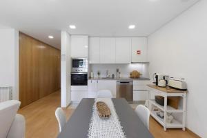 a kitchen with white cabinets and a table and chairs at Vale viver in Vale de Cambra