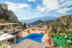 a resort with a pool and mountains in the background at Garden Cottage I Dammusi - Limoni in Castelmola