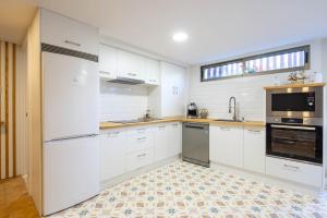 a kitchen with white cabinets and a sink and a refrigerator at Almar in Vigo +17 photos
