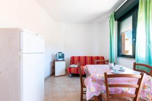 a dining room with a table and a refrigerator at Appartamenti Cavour codice F in Villasimius
