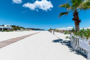 a boardwalk on the beach with a palm tree at Appartamenti Cavour codice F in Villasimius