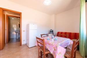 a dining room with a table and a refrigerator at Appartamenti Cavour codice F in Villasimius +17 photos