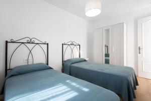 two beds in a white room with blue sheets at Penthouse 3A in Morro del Jable