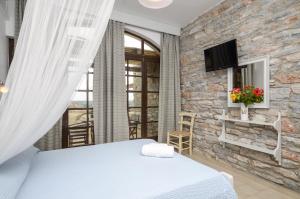 a bedroom with a bed and a stone wall at Victoria Studios & Apartments in Mikri Vigla
