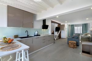 a kitchen with white cabinets and a living room at Casa Mara 2 in Playa Quemada
