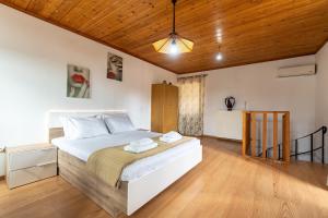 a bedroom with a large white bed with a wooden ceiling at Serenity Paxos in Gaios