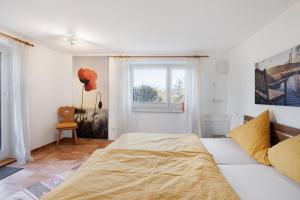 a white bedroom with a bed and a window at Birkethof Teichblick in Grimoldsried