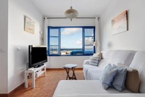 a living room with a white couch and a tv at Casa Vivo in Famara