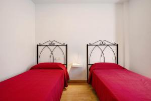 two beds in a room with red sheets at Apartamento Playa Morro Jable 1a in Morro del Jable