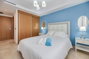 a bedroom with a large white bed with blue walls at Acogedor apartamento 2 dormitorios in Marbella +19 photos