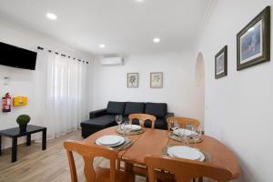 a dining room with a table and chairs and a couch at Quinta Alegre Tavira T1 in Luz de Tavira