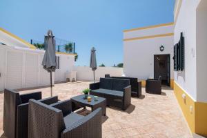 a patio with chairs and tables and umbrellas at Quinta Alegre Tavira T1 in Luz de Tavira