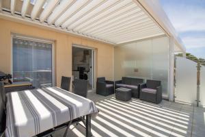 a patio with a bed and chairs on a balcony at Superbe Appart Neuf Climatisé in Albitreccia +20 photos