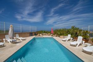 a swimming pool with lounge chairs and a umbrella at Superbe Appart Neuf Climatisé in Albitreccia