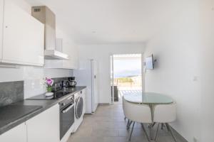 a kitchen with white cabinets and a table and a sink at Superbe Appart Neuf Climatisé in Albitreccia