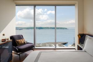 a bedroom with a bed and a chair and a large window at Thompson Seattle, by Hyatt in Seattle