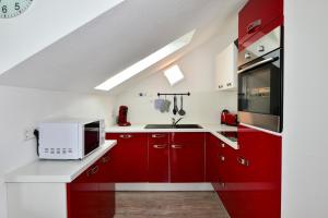 a kitchen with red cabinets and a microwave at Domicilio Azzurro in Lindau