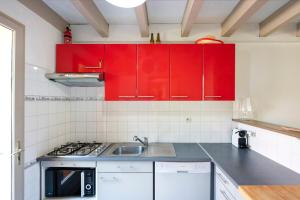 a kitchen with red cabinets and a sink at Maison Chaleureuse Avec Terrasse in Capbreton +18 photos