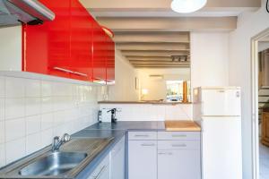a kitchen with a sink and a red cabinet at Maison Chaleureuse Avec Terrasse in Capbreton