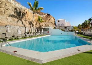 a swimming pool with chairs and a rock wall at Casita Blanca in Puerto Rico de Gran Canaria