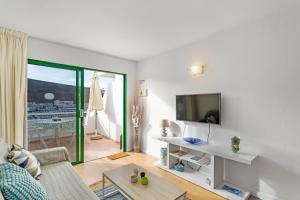 a living room with a couch and a tv at Casita Blanca in Puerto Rico de Gran Canaria