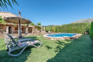 a yard with a chair and an umbrella and a swimming pool at La Sorteta De Cuxach in Pollença