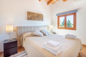 a white bedroom with a bed with two towels on it at La Sorteta De Cuxach in Pollença +27 photos