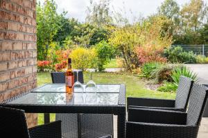 a glass table with bottles of wine on a patio at Großes Ferienhaus Im Grünen - in Dummerstorf