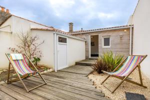 two chairs sitting on a wooden deck in front of a house at Agréable Maison Sablaise in Les Sables-d'Olonne