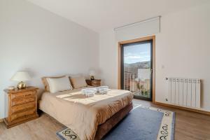 a bedroom with a large bed and a large window at Casa Vilarinha Gerês in Bouro