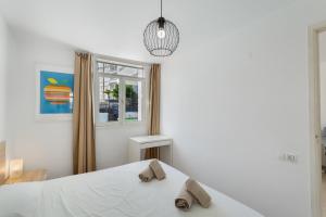 a white bedroom with a bed with slippers on it at Apartamento Yumbo Centro in Maspalomas