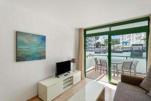 a living room with a couch and a tv and a balcony at Apartamento Yumbo Centro in Maspalomas