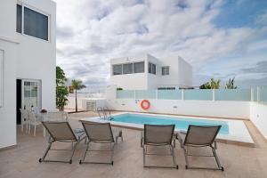 a white house with a swimming pool and chairs at Villa Khaleesi in Playa Blanca