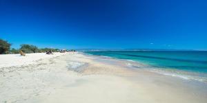 a beach with people sitting on the sand and the water at Attilio's House in Capoterra