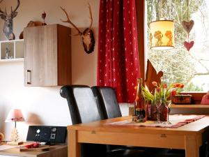 a dining room table with chairs and a red curtain at Haus Jurisch in Urberg