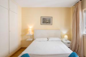 a bedroom with a white bed and two lamps at Oasis in Sitges +21 photos
