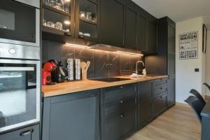 a kitchen with black cabinets and a wooden counter top at Annecy Garden Spa Billiards in Annecy +16 photos