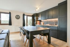 a kitchen with black cabinets and a table and chairs at Annecy Garden Spa Billiards in Annecy