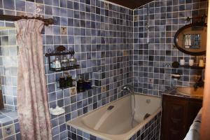a blue tiled bathroom with a tub and a sink at Gîte De Diane in Allemagne-en-Provence