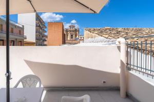 a balcony with a white wall and an umbrella at Il cappello sulle 23 in Avola